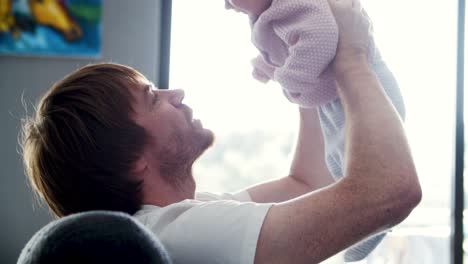 Happy-dad-holding-baby-daughter-in-air
